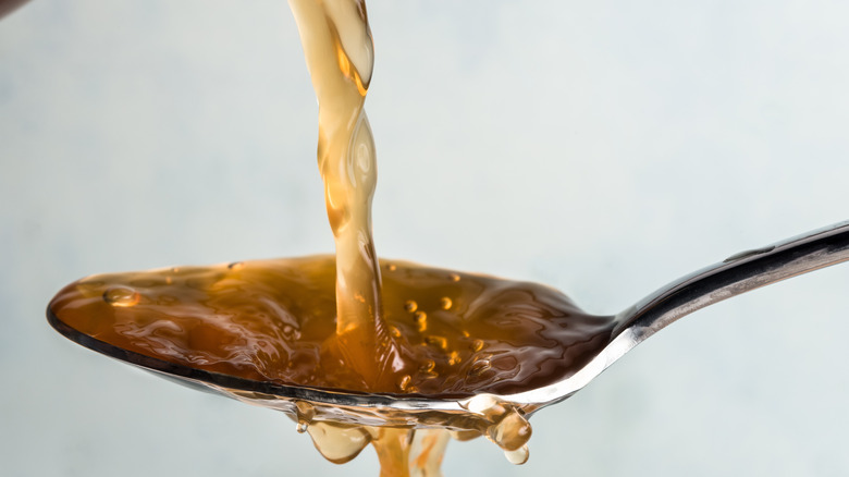 Apple cider vinegar being poured onto a spoon