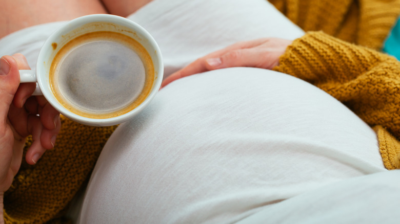 Pregnant woman holding cup of coffee