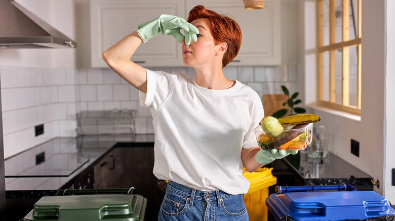 woman holding nose and tossing bad fruit