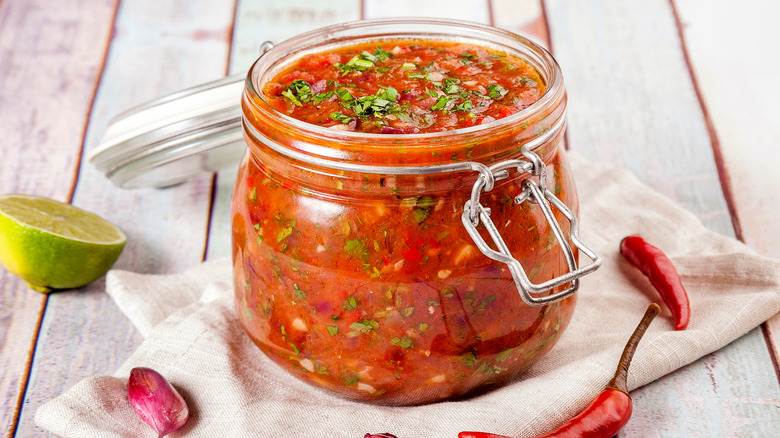 Hot sauce in glass jar with peppers