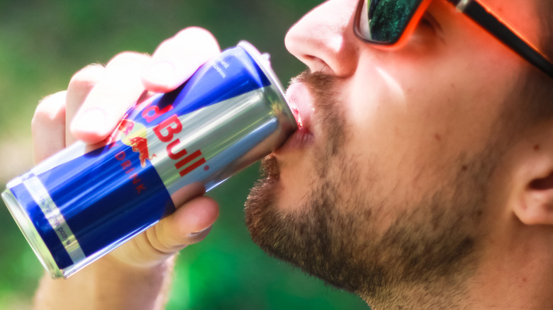 man drinking red bull energy drink