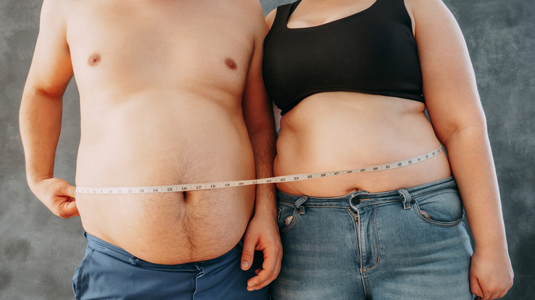 overweight couple with measuring tape around bellies