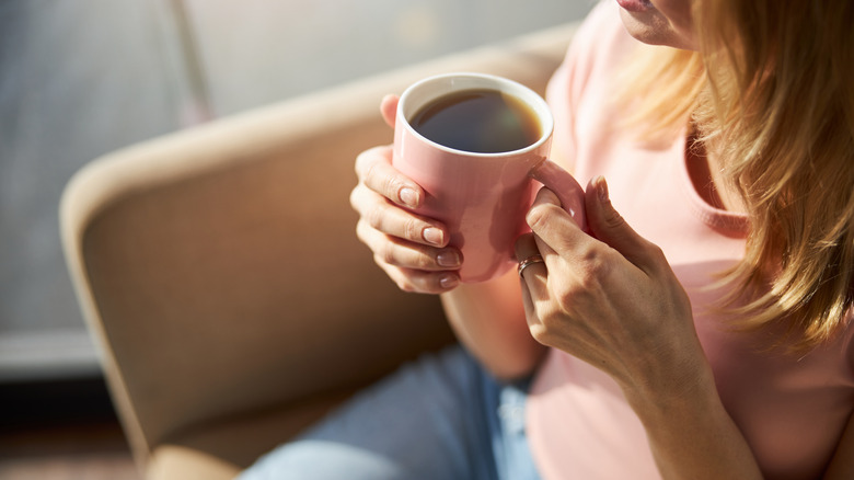 A woman holds a cup of coffee