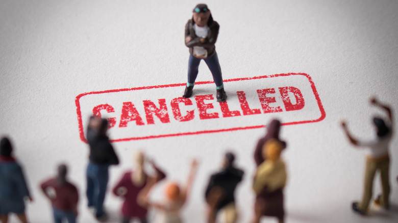 figure standing on 'cancelled' label