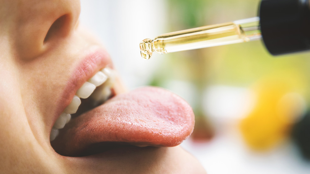 Person dropping CBD oil onto their tongue