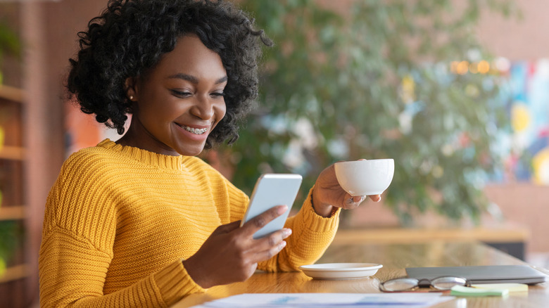 Woman holding coffee cup and phone 