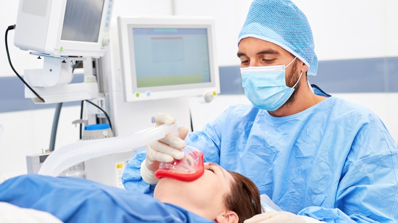 doctor holding mask on woman's face during surgery