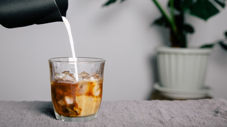 Pouring cream into a cup of coffee