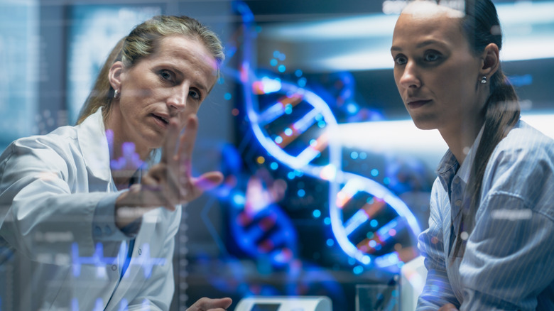 A doctor explaining to a patient about cancer using graphics of DNA and chromosomes
