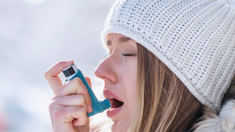 Woman using asthma inhaler in winter