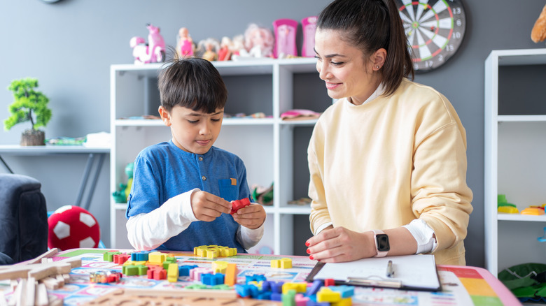 boy using building blocks with therapist