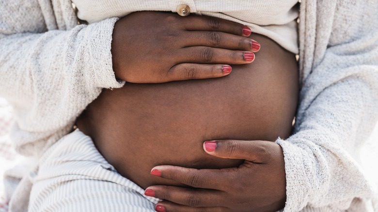 Pregnant person's hands on belly