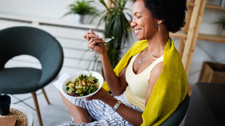 Woman sits with bowl of salad