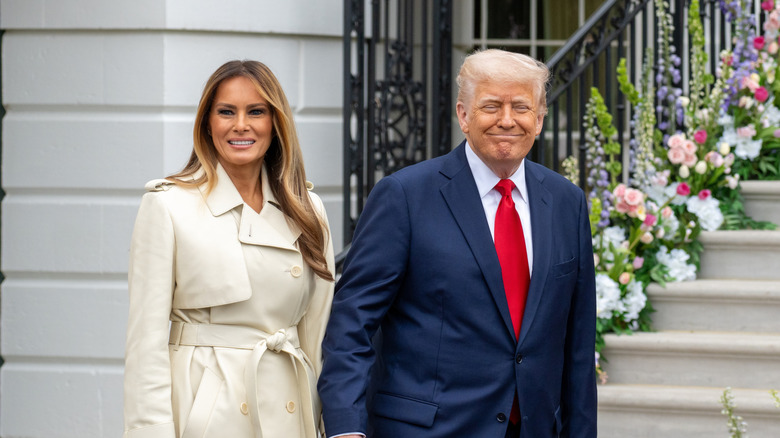 Donald and Melania Trump smiling and holding hands