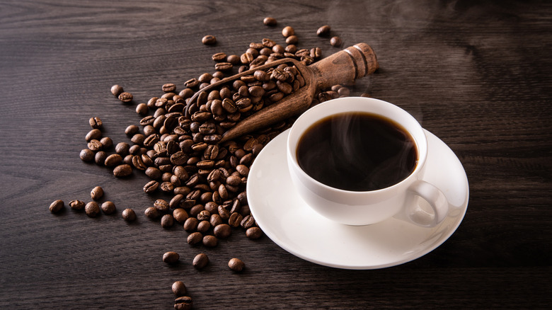 Cup of black coffee with coffee beans on the table