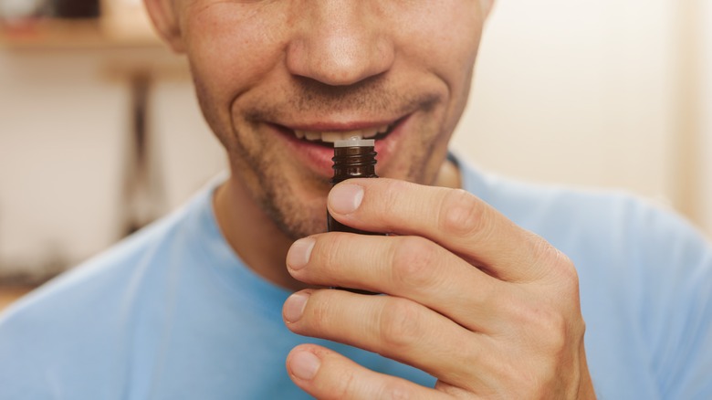 Smiling man sniffing essential oil