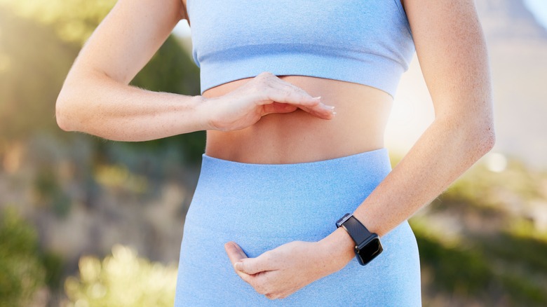 Woman holding hands above and below her abdomen