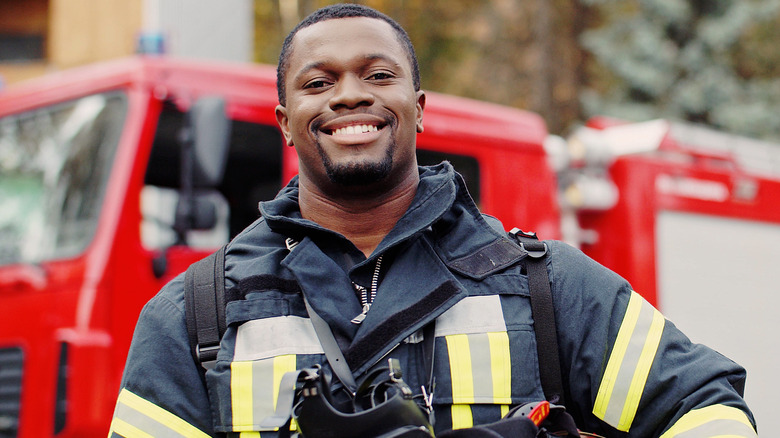 Young male firefighter posing in front of a fire truck 