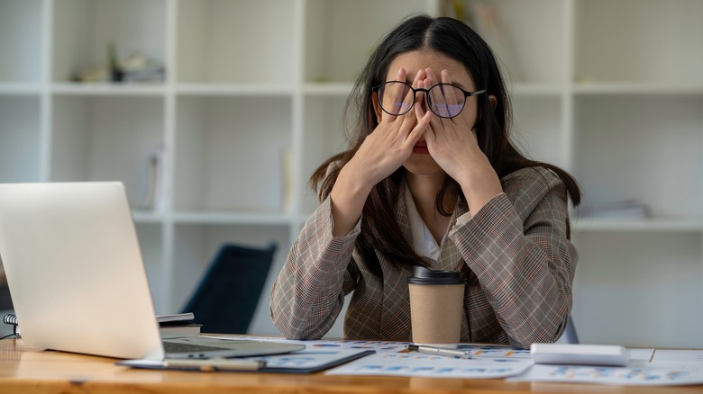 Person at desk rubbing eyes