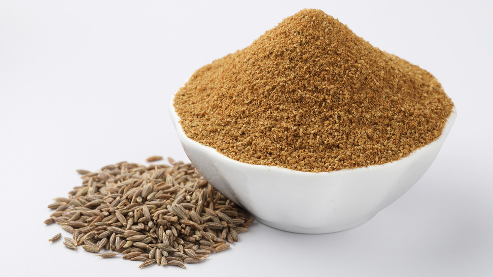 Cumin seeds and powder in white bowl