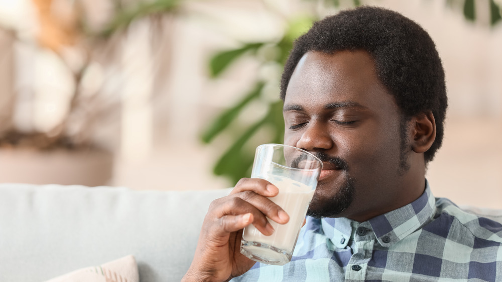 Woman drinking glass of goat milk 