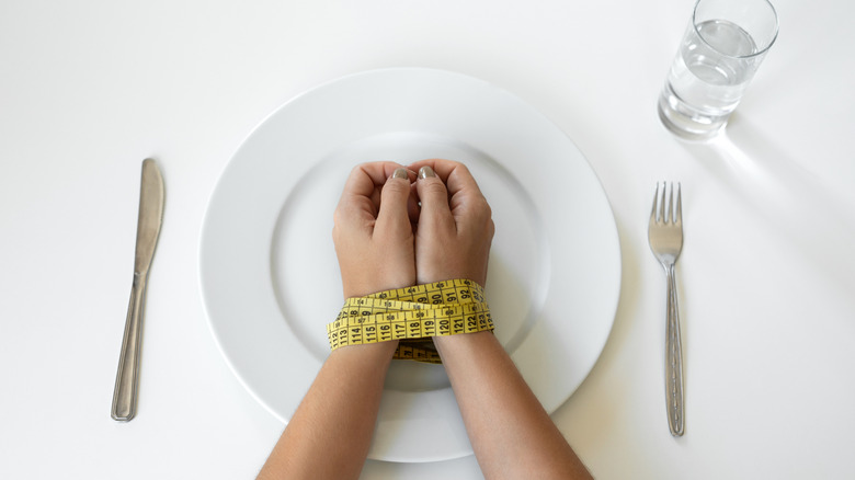 woman's hands tied in tape measure resting on plate