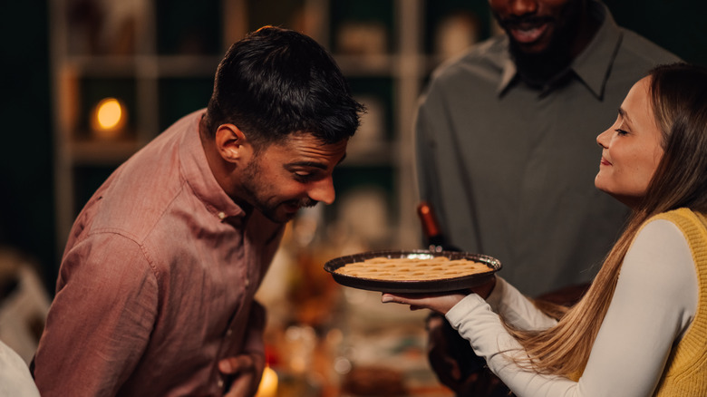 woman showing apple pie to man at party