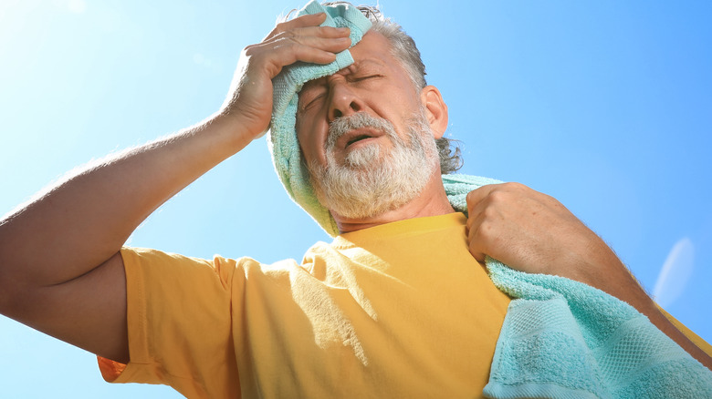 senior man holding towel under sun