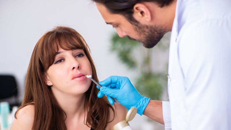 hispanic man applying ointment on cold sore