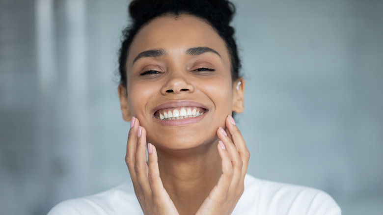 Woman smiling and touching her face