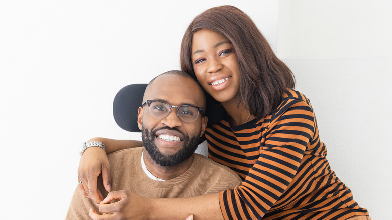 smiling man in a wheelchair with happy woman sitting by him