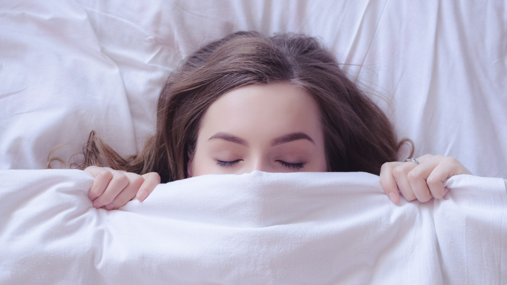 woman sleeping under the bed covers