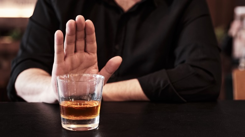 Person pushing away a drink and abstaining from alcohol