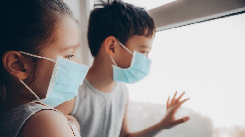 Children wearing masks looking out the window: quarantine concept