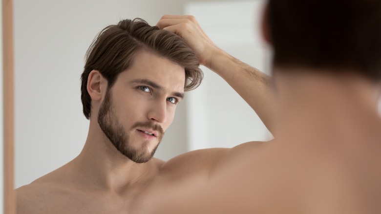 man looking at hair in the mirror