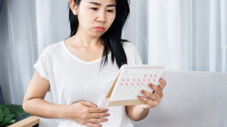 Unsure woman looking at menstrual calendar