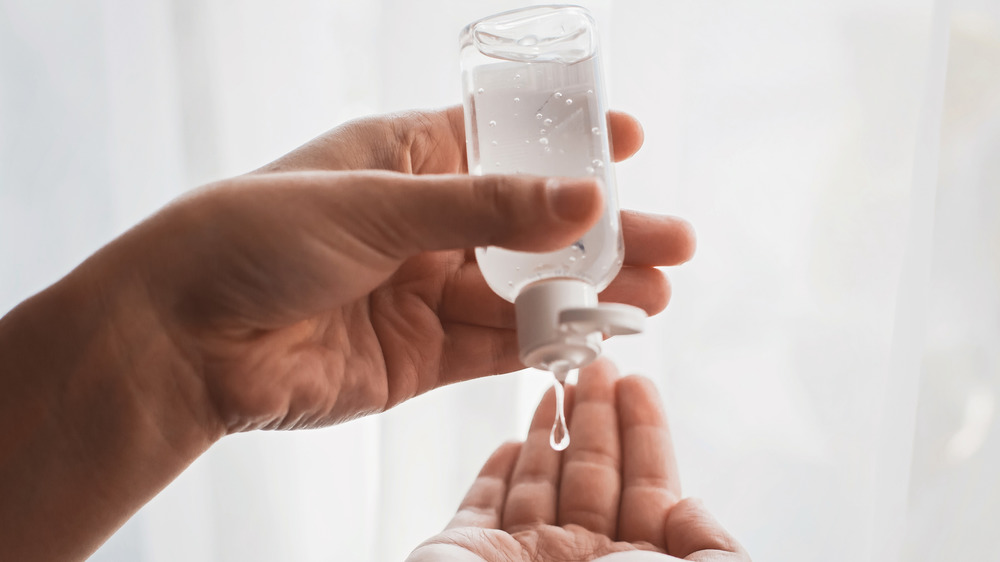 Hand sanitizer held in a left hand and squeezed into the palm of a right hand