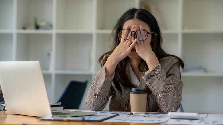woman holding hands over eyes due to pain