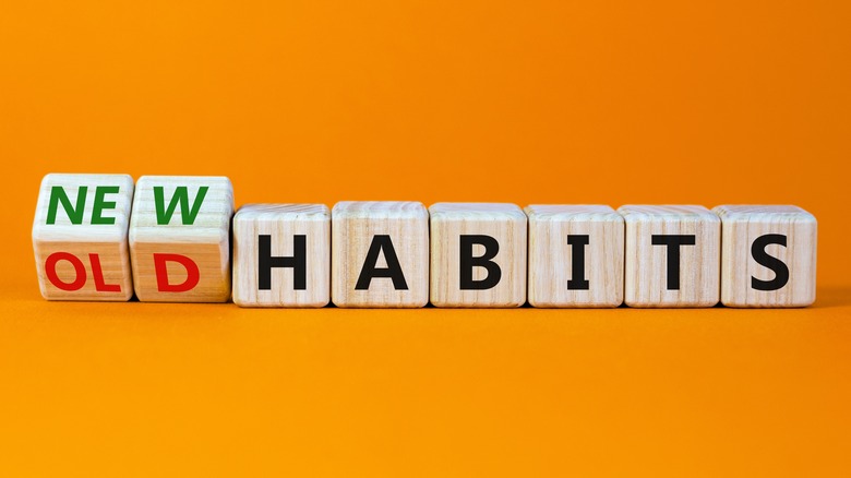 Wooden blocks reading "New" "Old" "Habits" on orange background