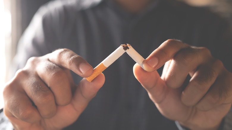 Pair of hands breaking apart a cigarette