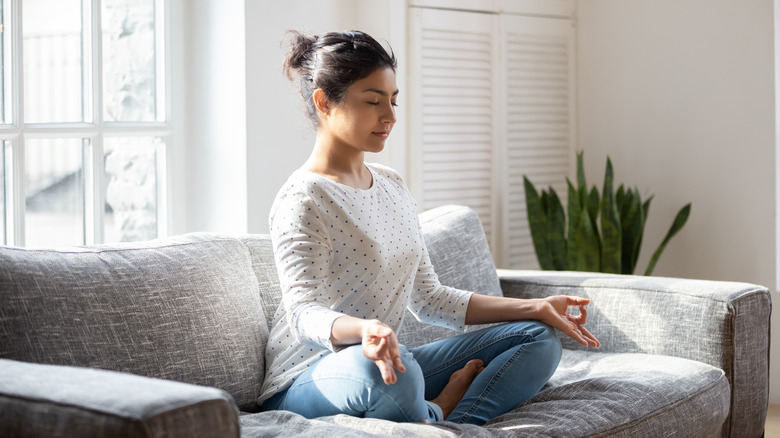 Young woman sitting and meditating on couch