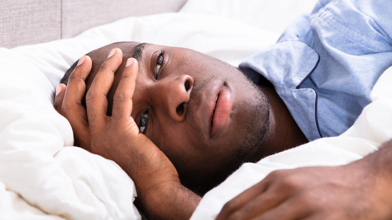 Man with hand on forehead lying in bed