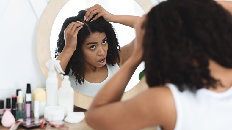 woman looking at hair loss in mirror
