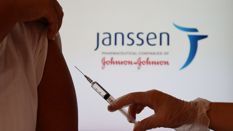Hand holding a syringe against woman's shoulder
