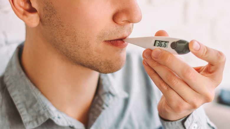 man taking temperature with thermometer