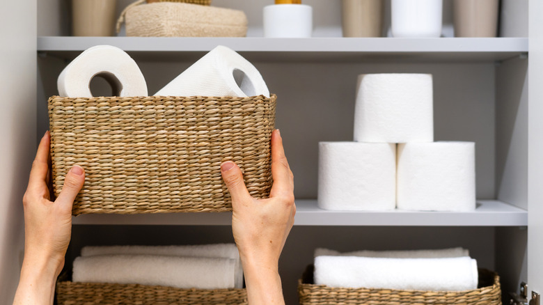 woman grabbing basket of toilet paper rolls from shelf