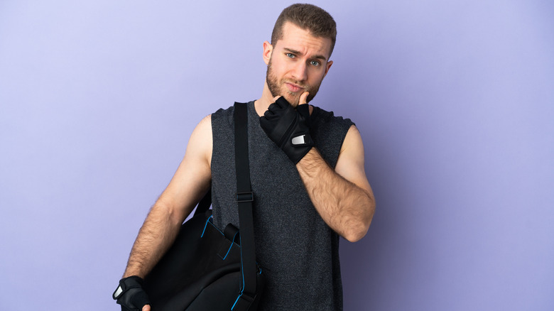 Contemplative man, holding a gym bag