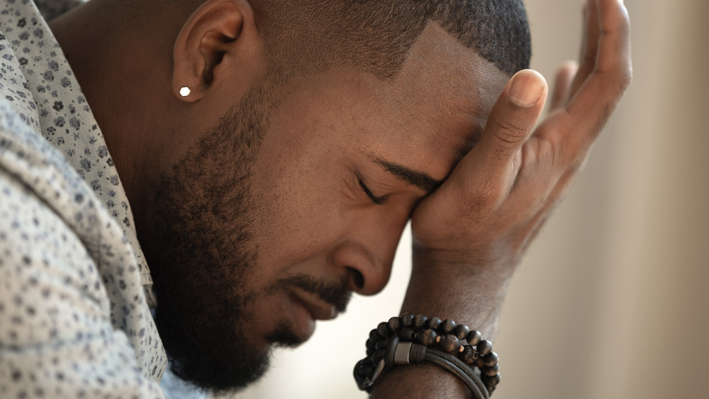 Person leaning forward with eyes closed and hand held to forehead