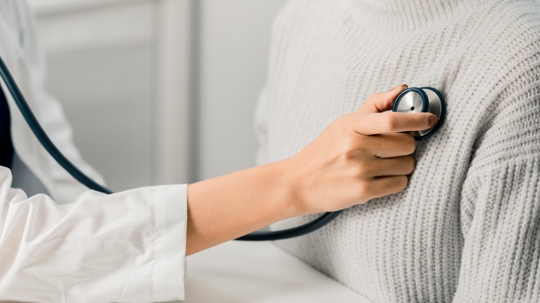 doctor checking patient's heart with stethoscope