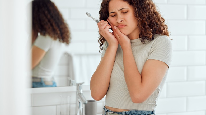 woman holding mouth in pain